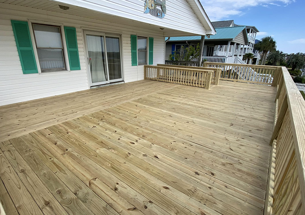 wooden deck with wooden railing, white siding for house, green shutters for windows