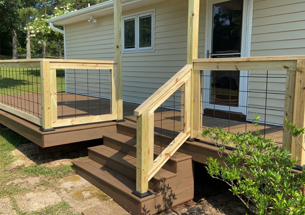 stairs leading to wooden deck with wooden railings, white siding on house, white framed windows and door, close up view