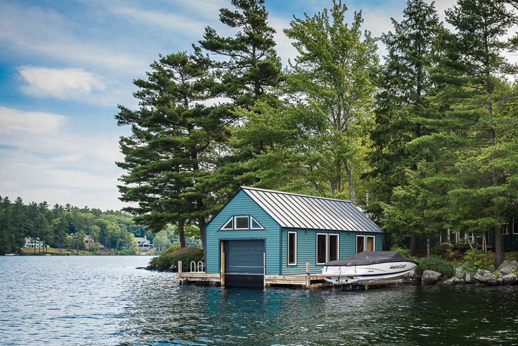 teal boathouse on a lake with boat