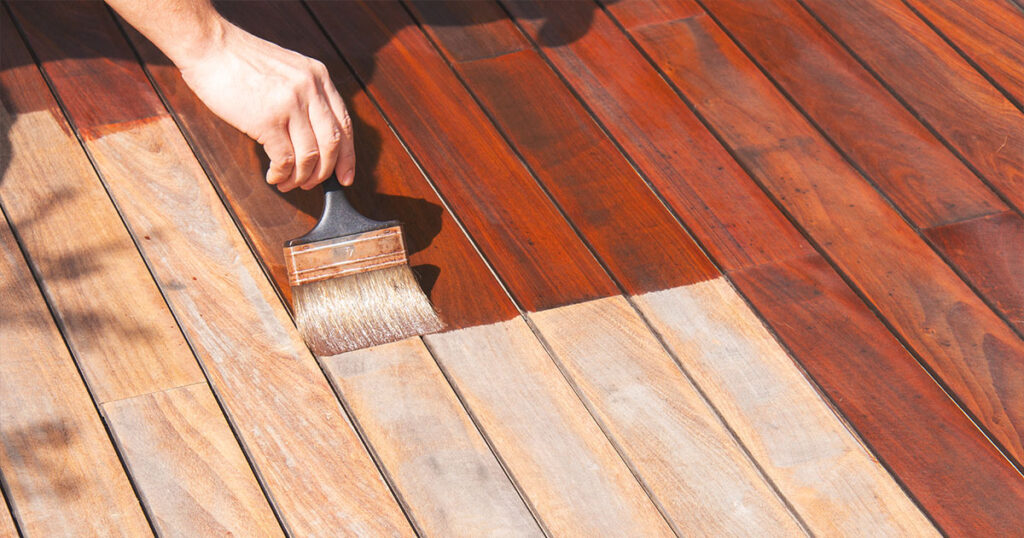Deck painting, worker is painting ipe deck with a painting brush