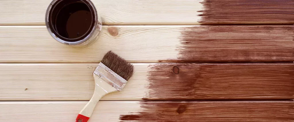 Painting a wooden deck with a paintbrush