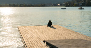 silhouette of a woman relaxing on a floating dock on a lake at sunset