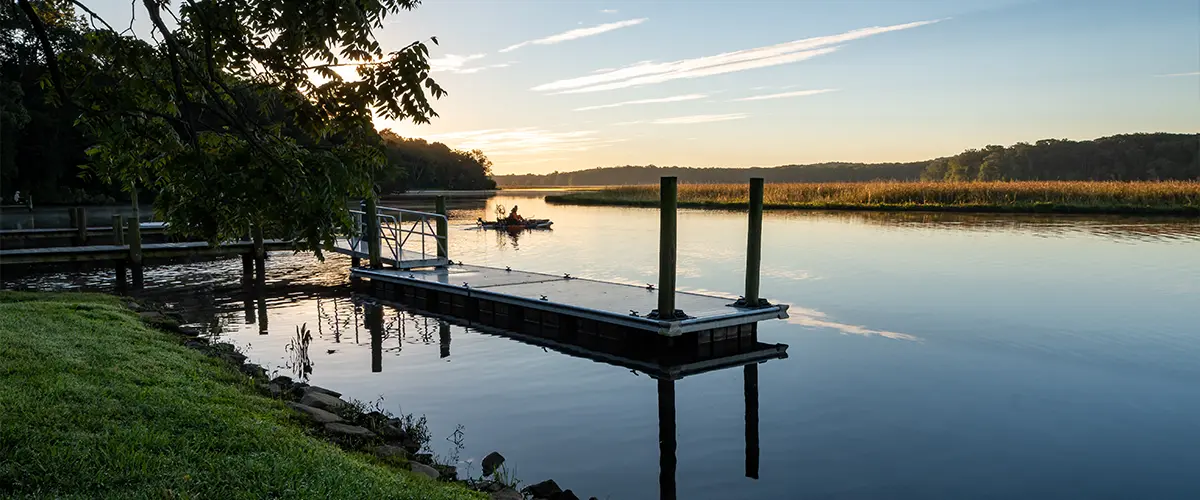 Lone Small Fishing Boat Near Floating Dock on a Calm River in Autumn at Sunrise