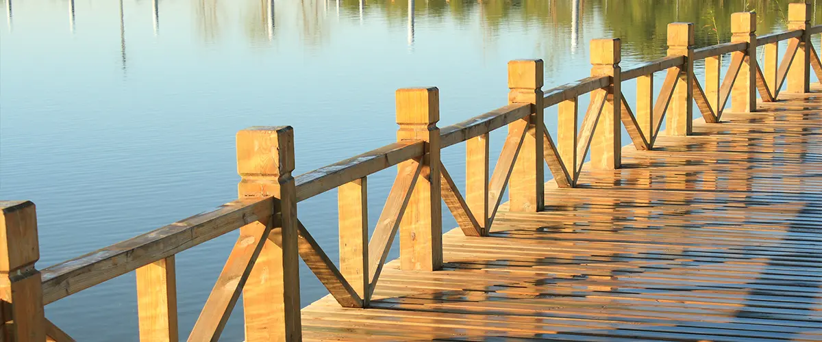 Sunlit dock building scene with calm lake reflections.