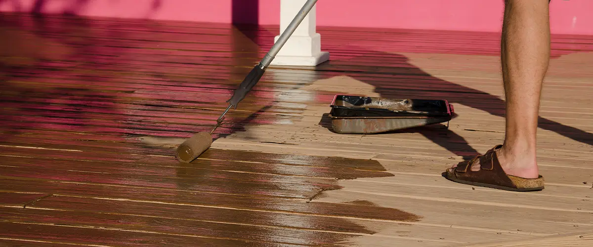 Sealing a wooden deck with a roller brush, enhancing the outdoor space with a protective finish.