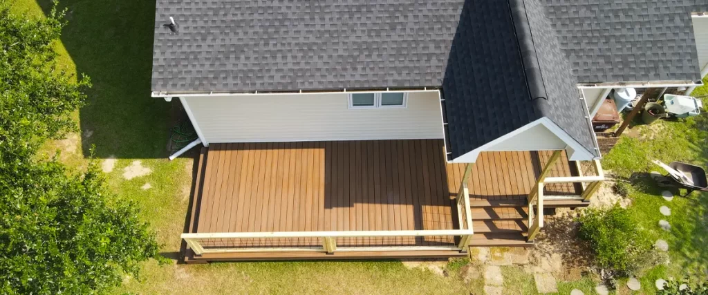 Aerial view of newly built composite deck with modern cable railing on single-story house with shingled roof
