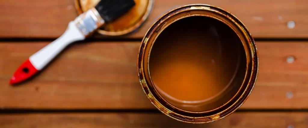 A paint can and brush resting on a wooden table, ready for a painting project
