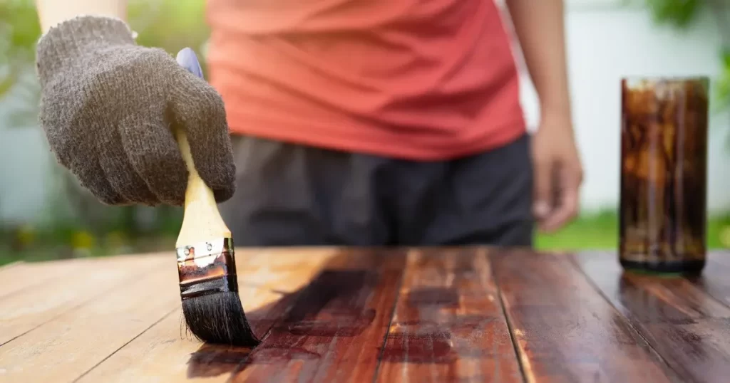 A person brushes dust off a wooden table, focusing on cleaning its surface