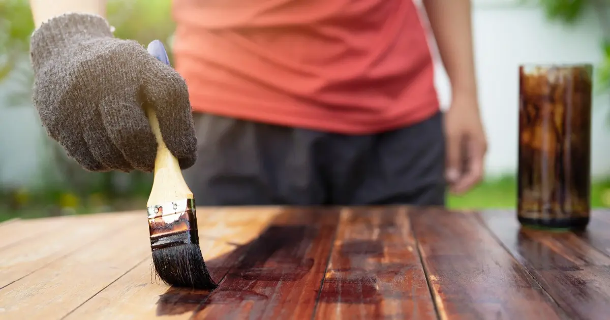 A person brushes dust off a wooden table, focusing on cleaning its surface