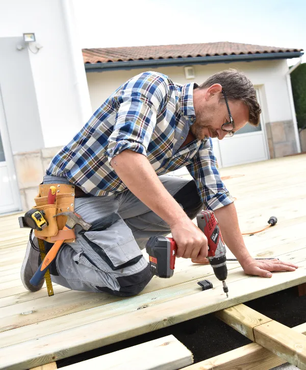 a deck contractor repairing decking boards with a power drill