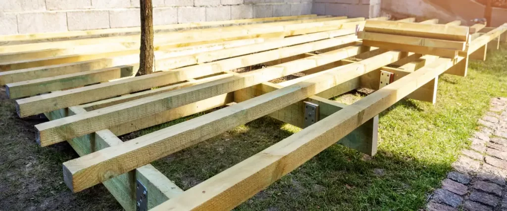 The initial stage of deck planning showing the wooden joists and frame layout positioned around a tree trunk.