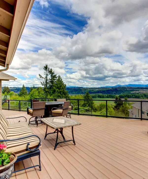 Expansive backyard deck with black glass railings and outdoor furniture overlooking a scenic valley, constructed by deck building companies in Garner, NC.