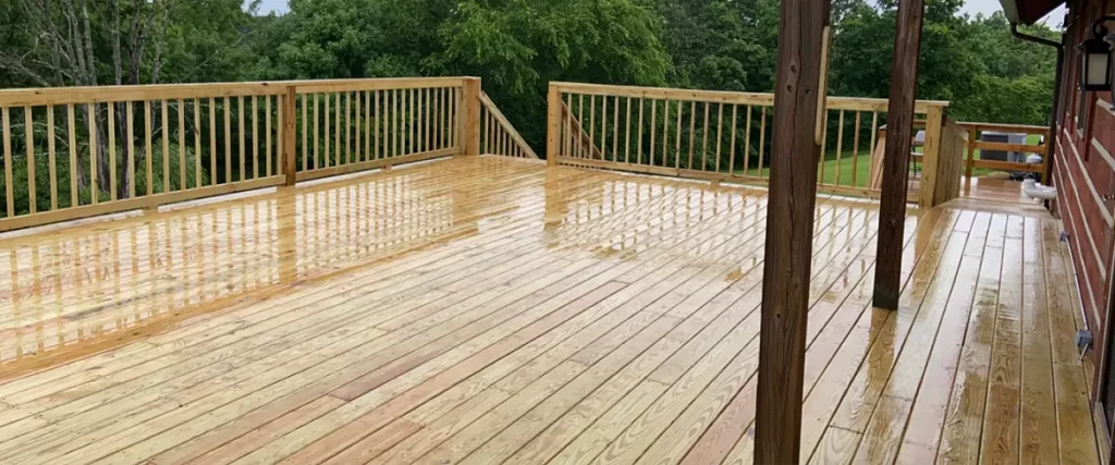 Custom pressure-treated wood deck with stairs and railing overlooking wooded backyard